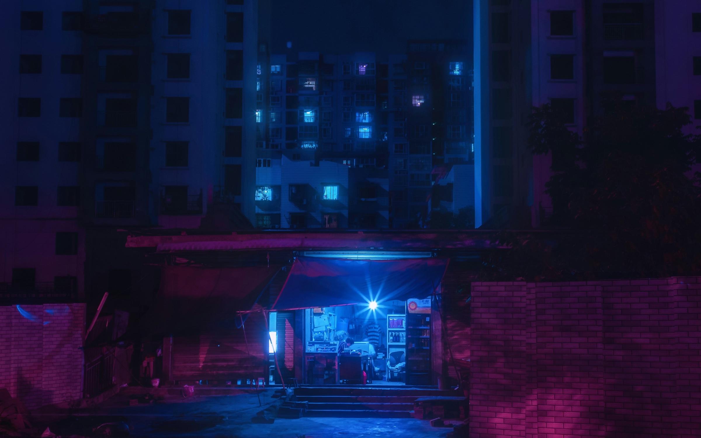An open storefront glowing with blue light at night