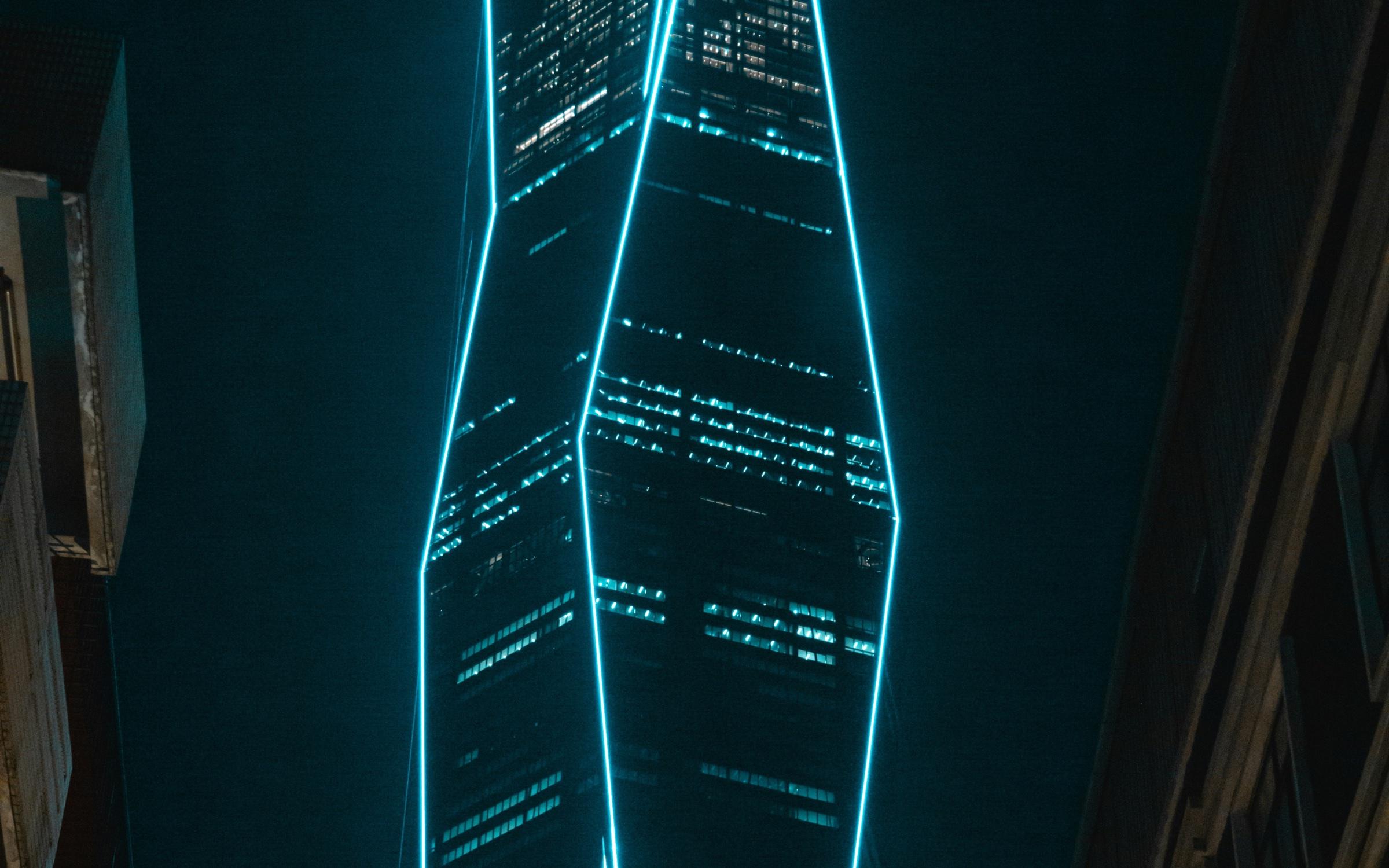 A tower traced with bright cyan light against the night sky